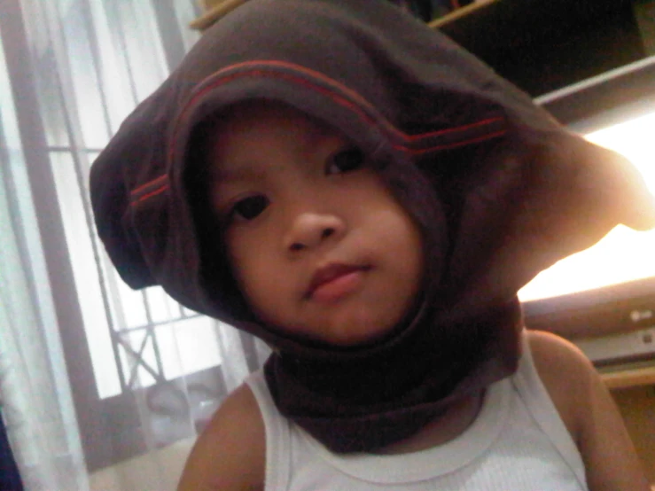 a little boy wearing a hood and looking in the mirror