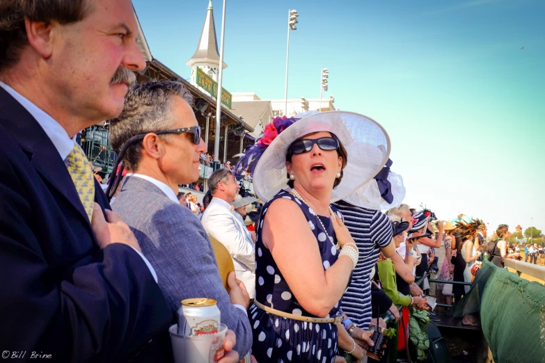 a crowd watches as two women in hats sing