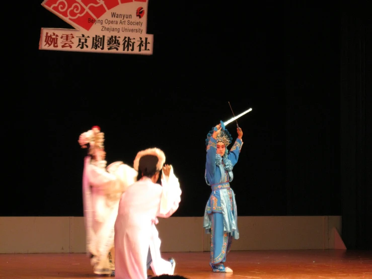 two woman and a man perform in a traditional dance