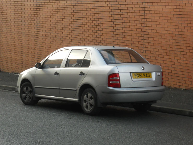 a silver car is parked by a brick wall