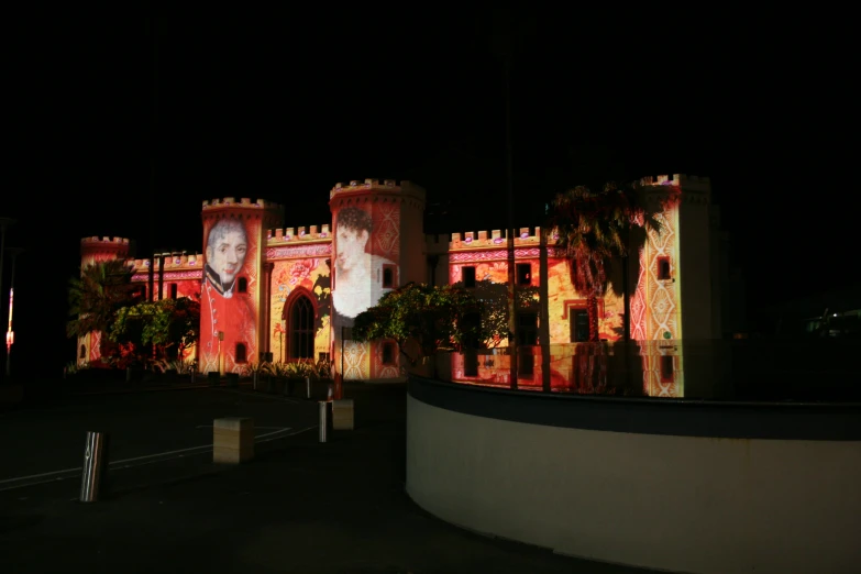 a castle lit up in red with a woman on it