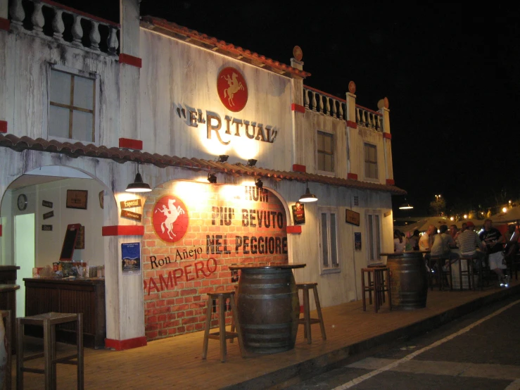 a restaurant on a street corner at night with signs hanging from the outside