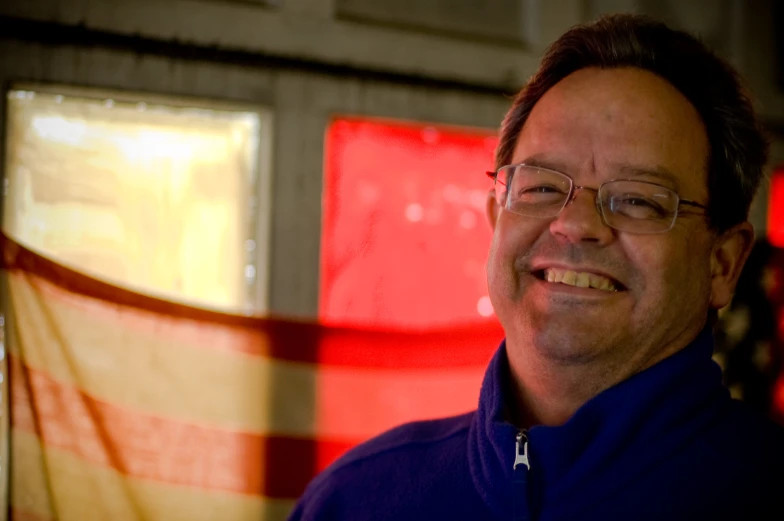 man in purple shirt and glasses with red wall