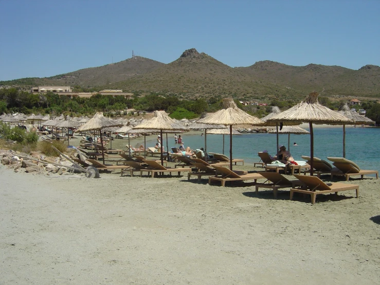 people sitting under umbrellas on a beach near the water