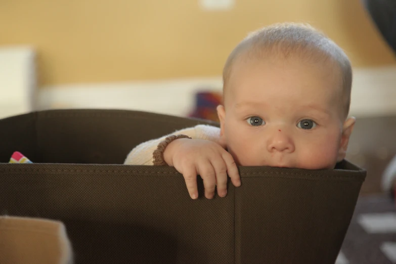 a small baby sitting in a brown basket