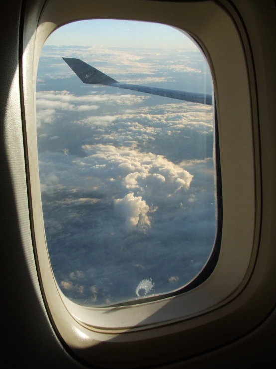 the wing of an airplane is seen through the clouds