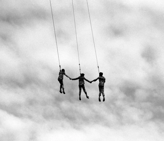 three people hanging from a rope on a parachute