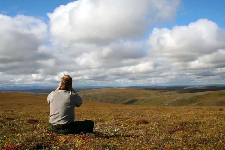 a man looking at the sky on top of a hill