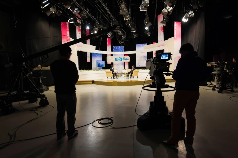 two guys stand in front of a screen in an empty studio