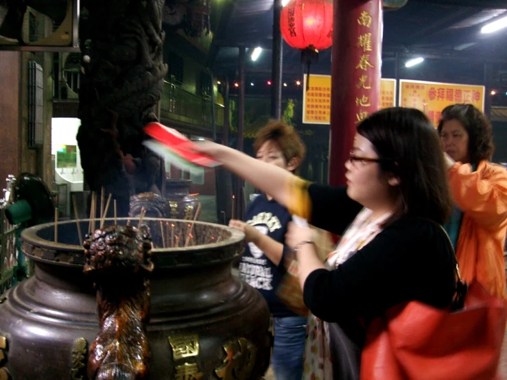 people standing in front of large vases with lights hanging from them