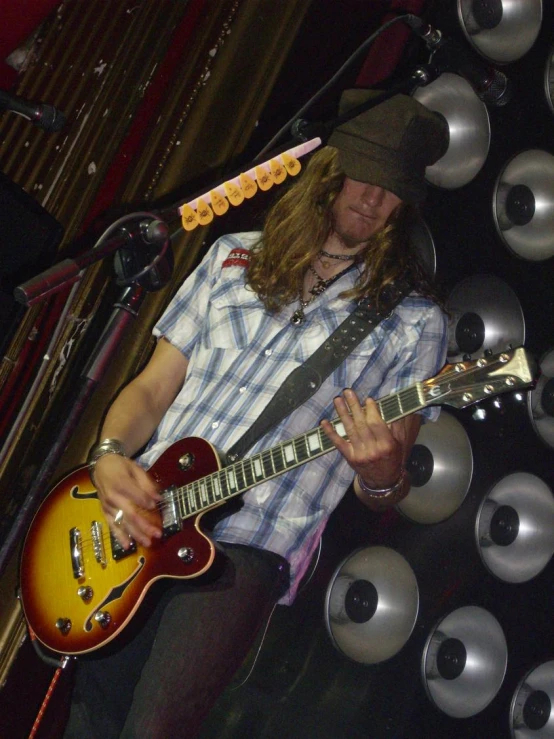 a young person playing a guitar in front of a speaker system