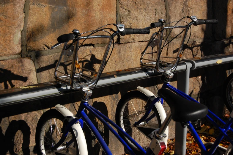 two bikes parked side by side against a stone wall