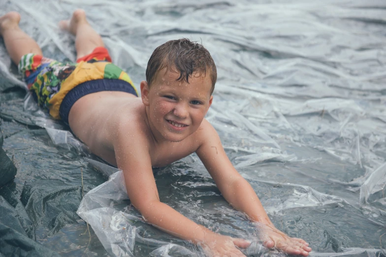 a smiling little boy rides on a surfboard