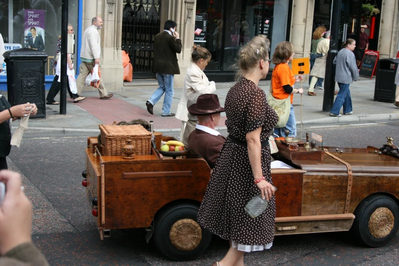 people in a city with an old car loaded with fruit