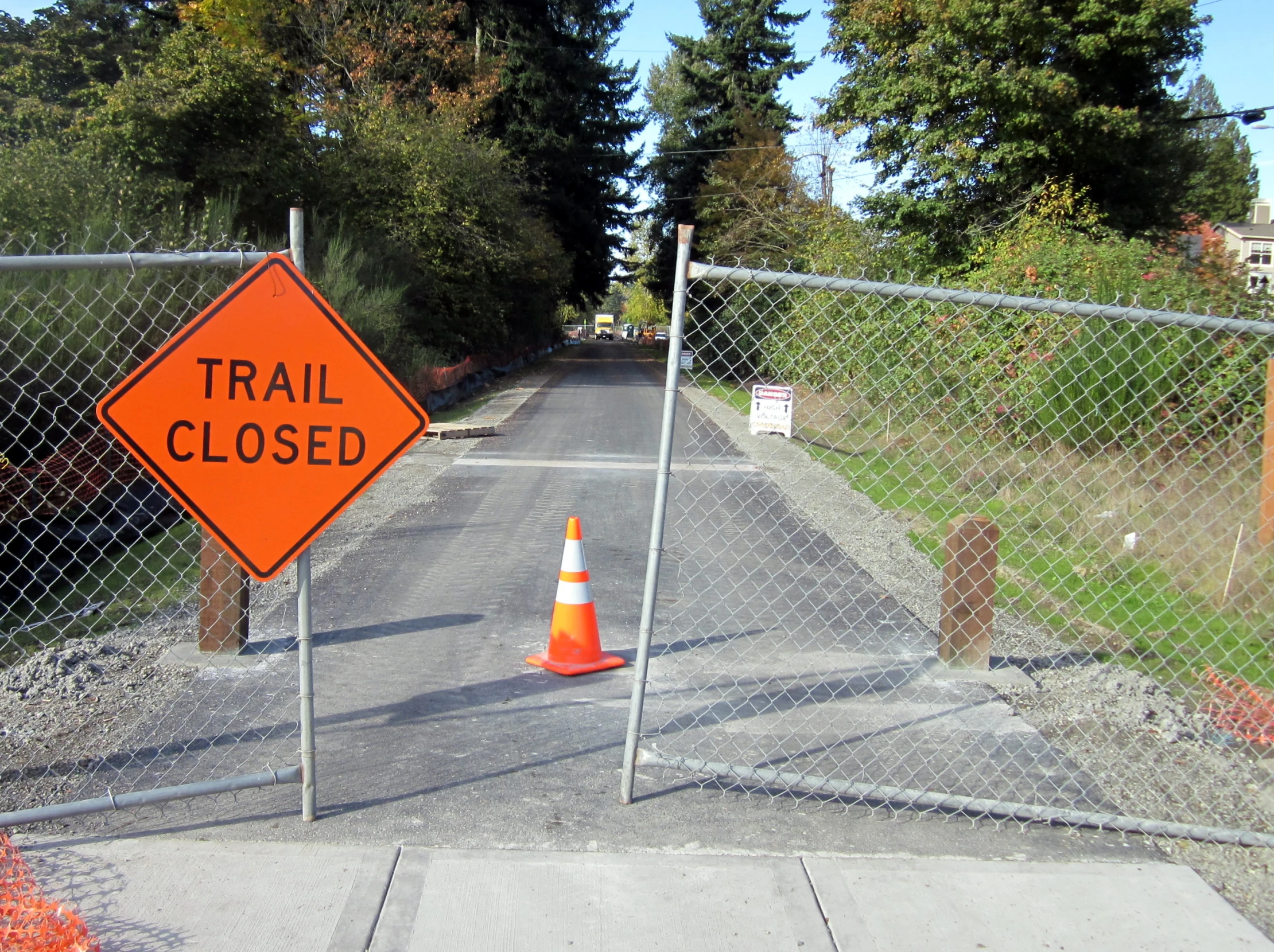 a sign showing the road closed is in between two fences