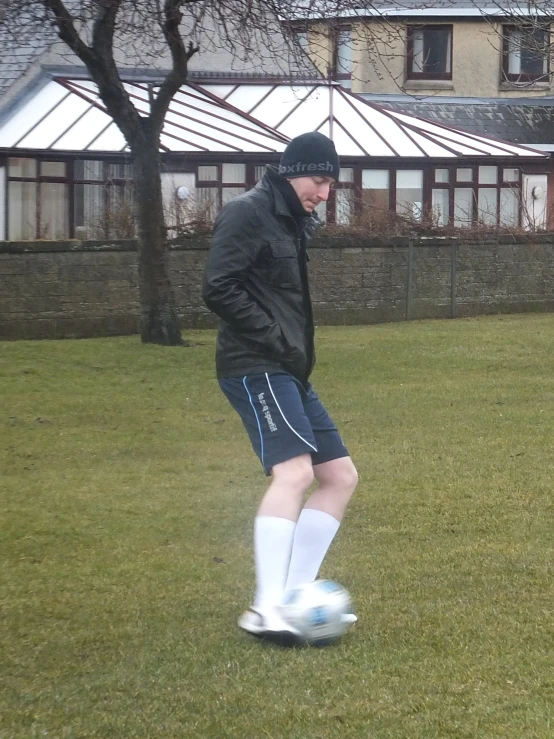 a man in black jacket kicking a soccer ball