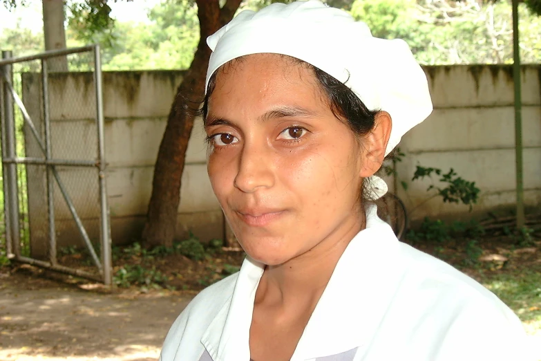 a woman dressed in white outside by some trees