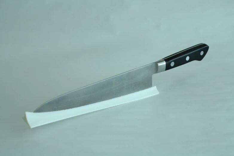 a large knife on a white surface near a wall