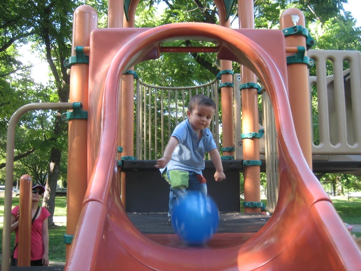 a boy playing in the playground with blue ball