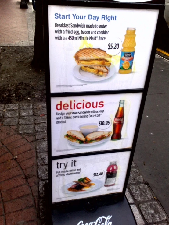 three signs on a city street that include sandwiches