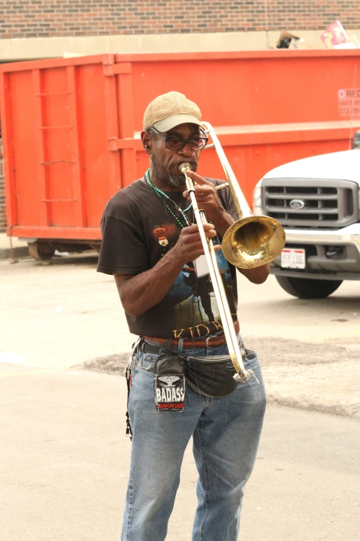 a man plays a trumpet in front of trucks