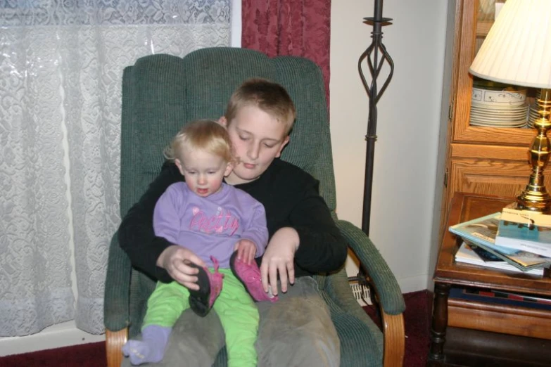 the woman sits with her child on the chair in front of a lamp