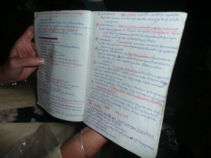 a hand holding a note book that is written in multiple languages