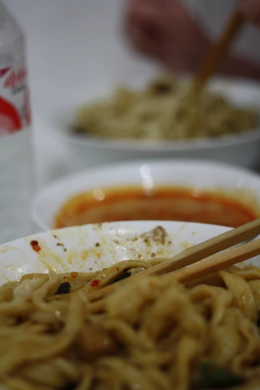 bowl of ramen with chopsticks sitting on a table with some asian food