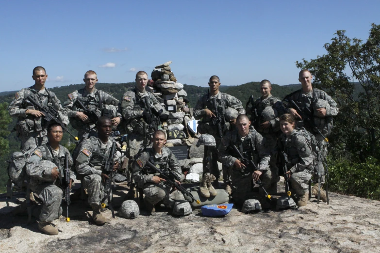 the group of army personnel with equipment pose for a group pograph