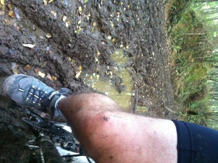 a close up view of a man with boots and socks in the mud