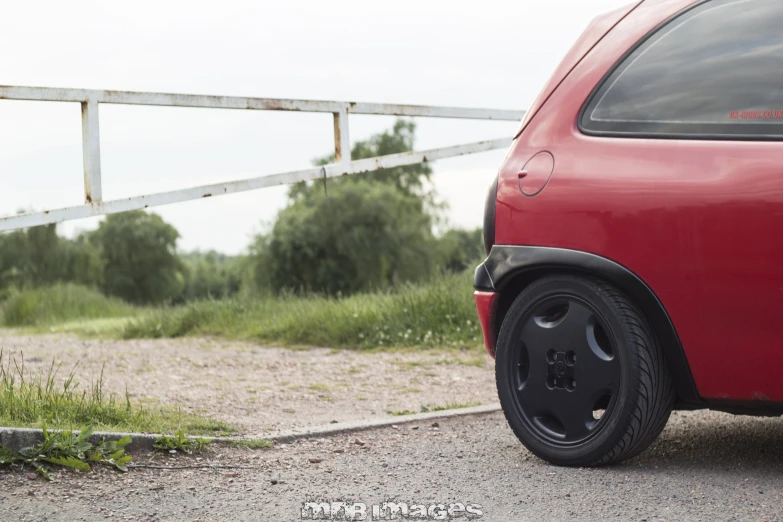 a red car sits parked next to a rail