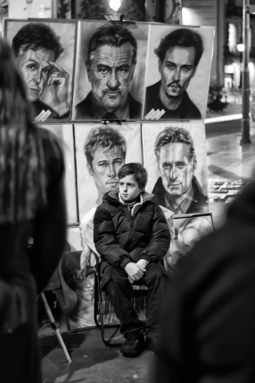 a man sitting in front of a portrait with some faces