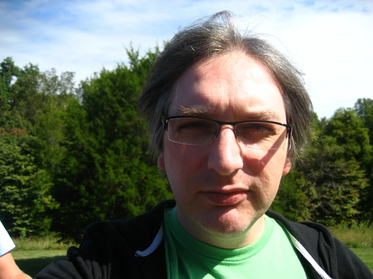 man wearing glasses with long hair in grassy area