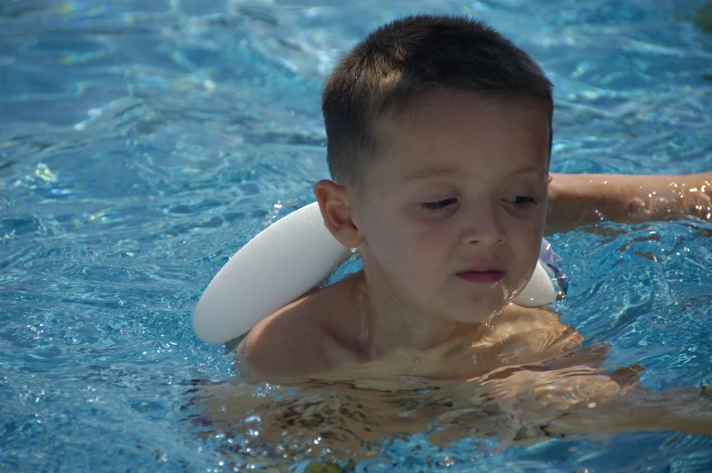 boy wearing white swim hat playing in pool