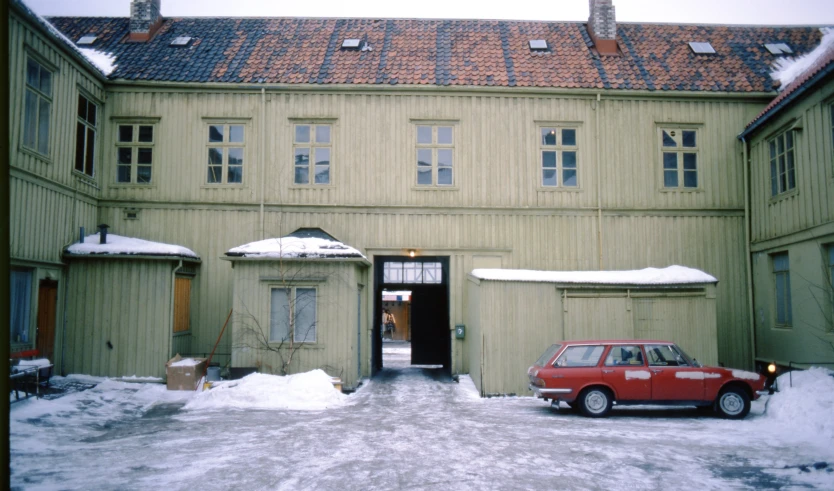 a car parked on the sidewalk next to a building with snow covering the windows