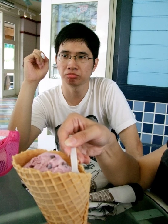 there is a man sitting down eating a scoop of ice cream