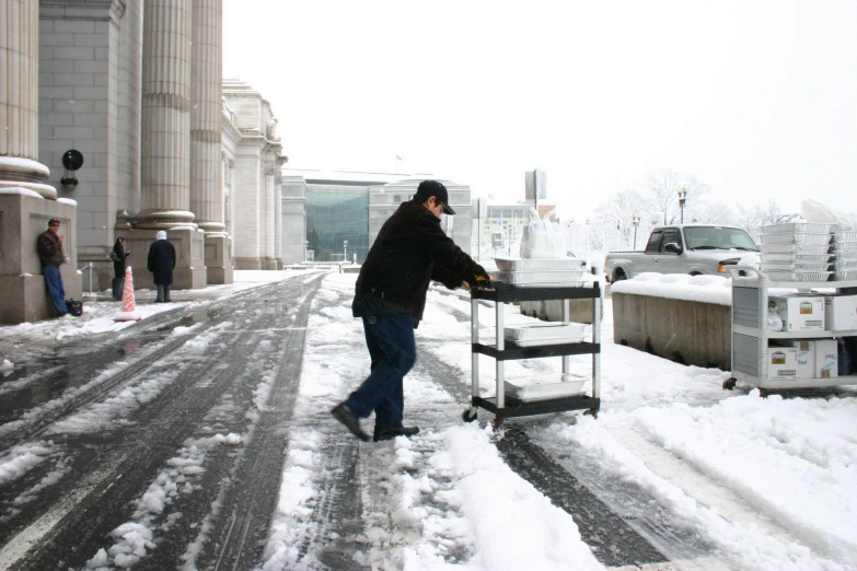 man shoveling snow from a bench near a street