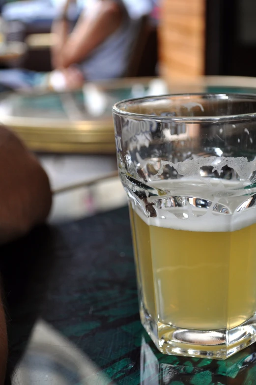 there is a half full glass of beer on a table