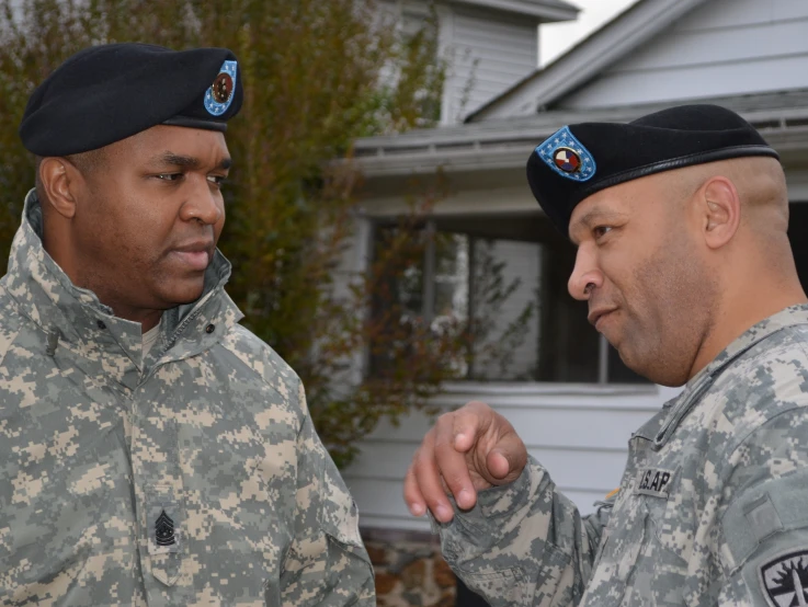 two military men standing outside a building talking