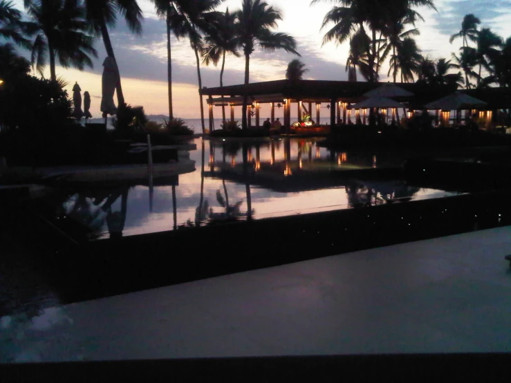 a resort pool with some lights reflecting in the water