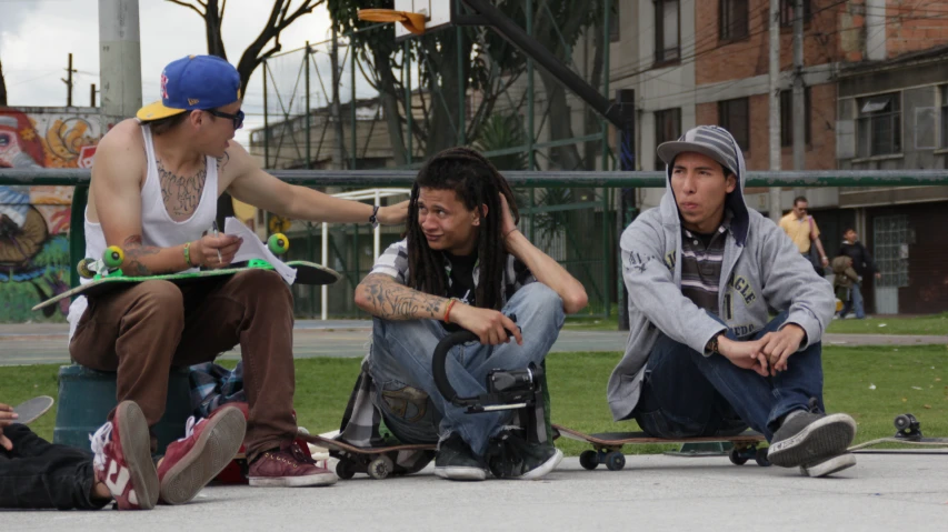 three men sitting on skateboards in front of a building