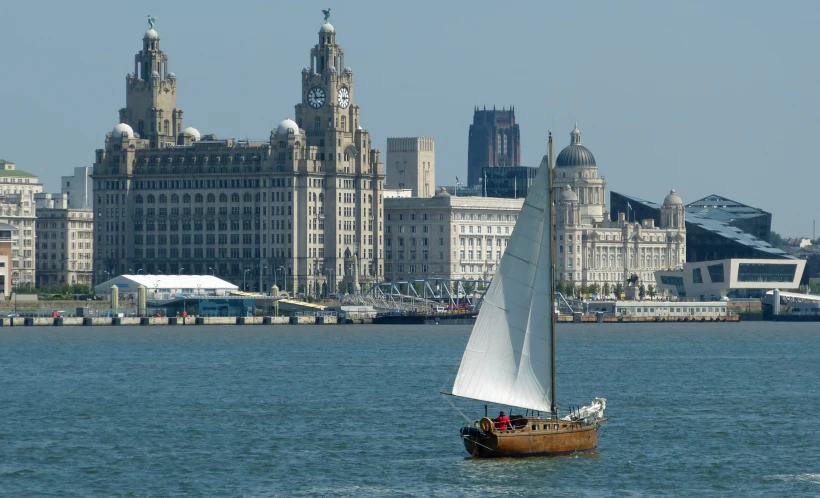 a sail boat sailing on the water in front of buildings