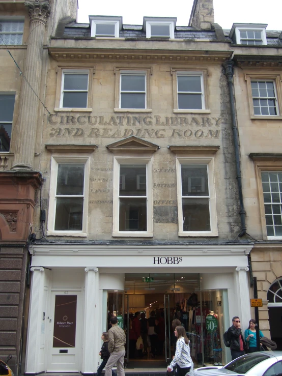 people standing and walking in front of a large building