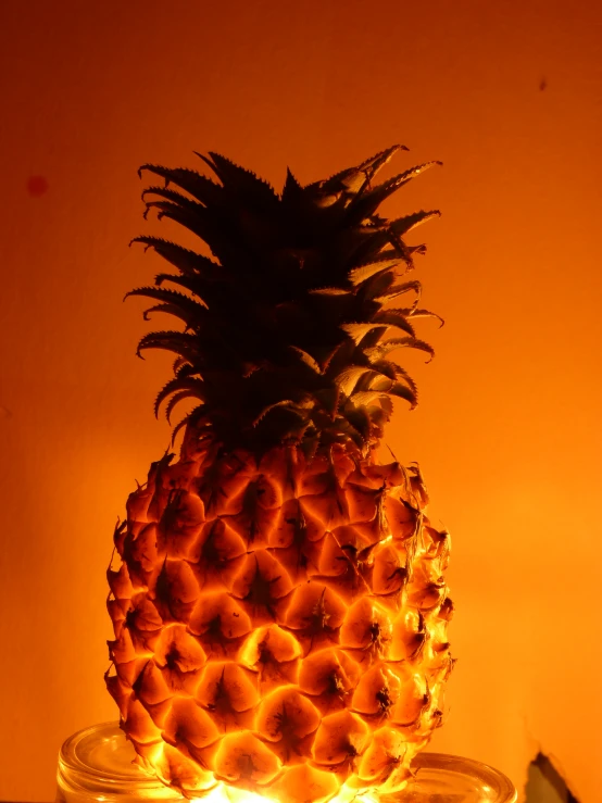 a pineapple in a glass jar with flames underneath