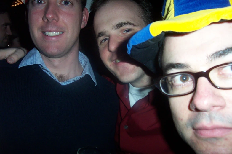 three men pose together in a crowd