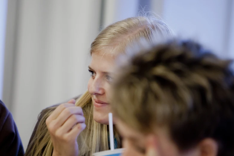 a woman using a toothbrush on top of a long blonde haired girl