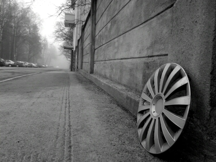 a very big wheel by a wall near the road