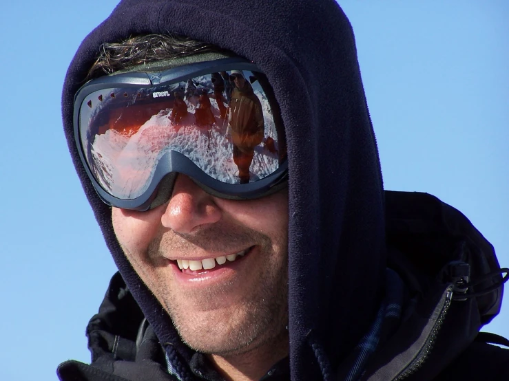 a man wearing ski goggles and a hood smiling