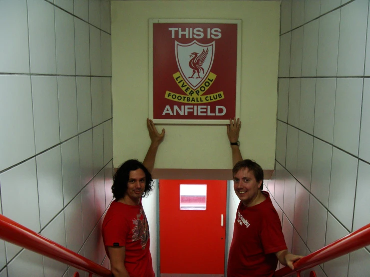 two men are standing by a closed door with arms up