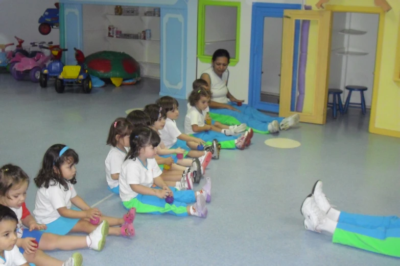 the child are sitting on a floor and watching the woman